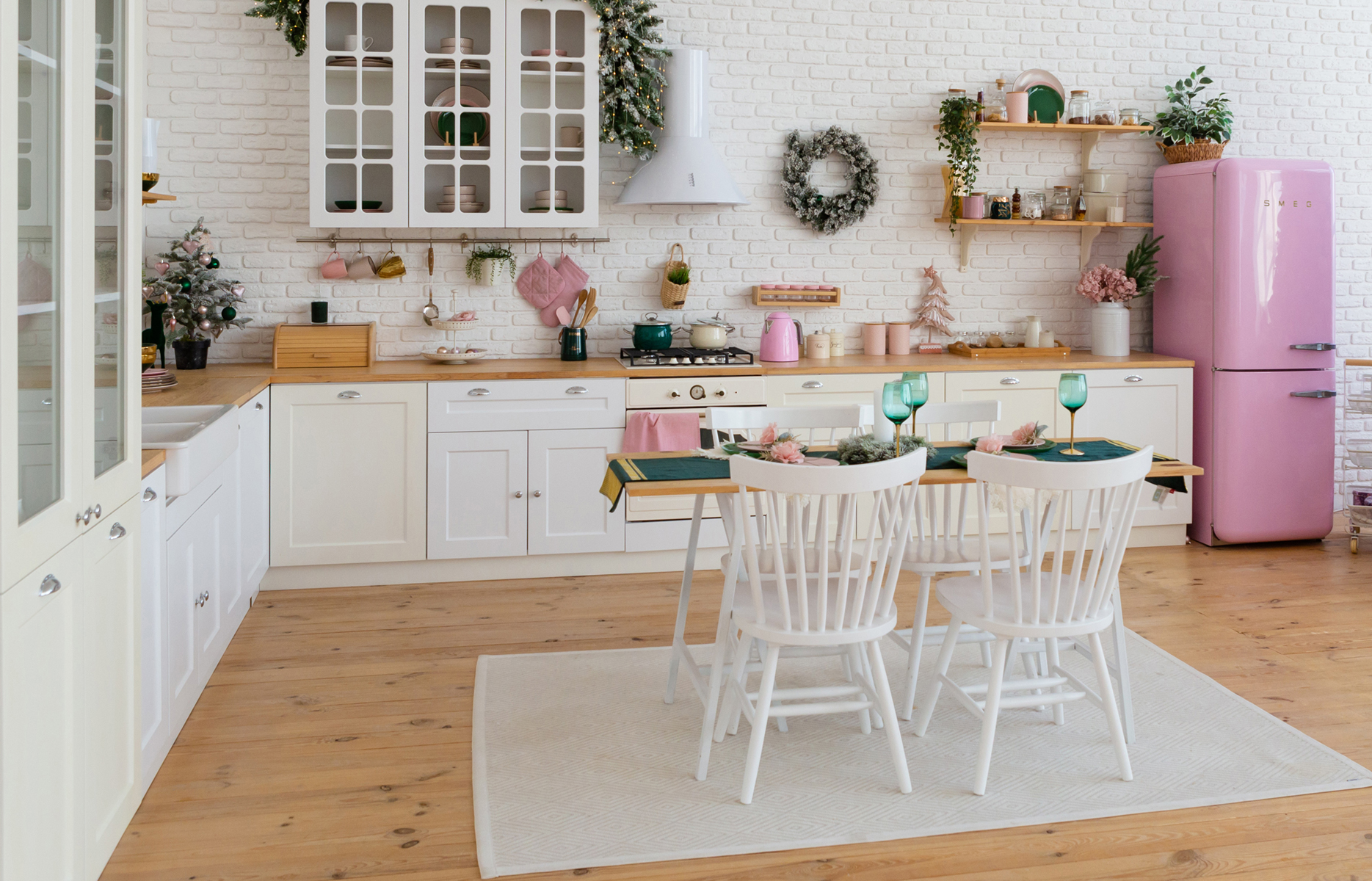 Modern kitchen with sink, served table, oven and white furniture. Kitchen with christmas decorations, pine tree. New year atmosphere appartment.