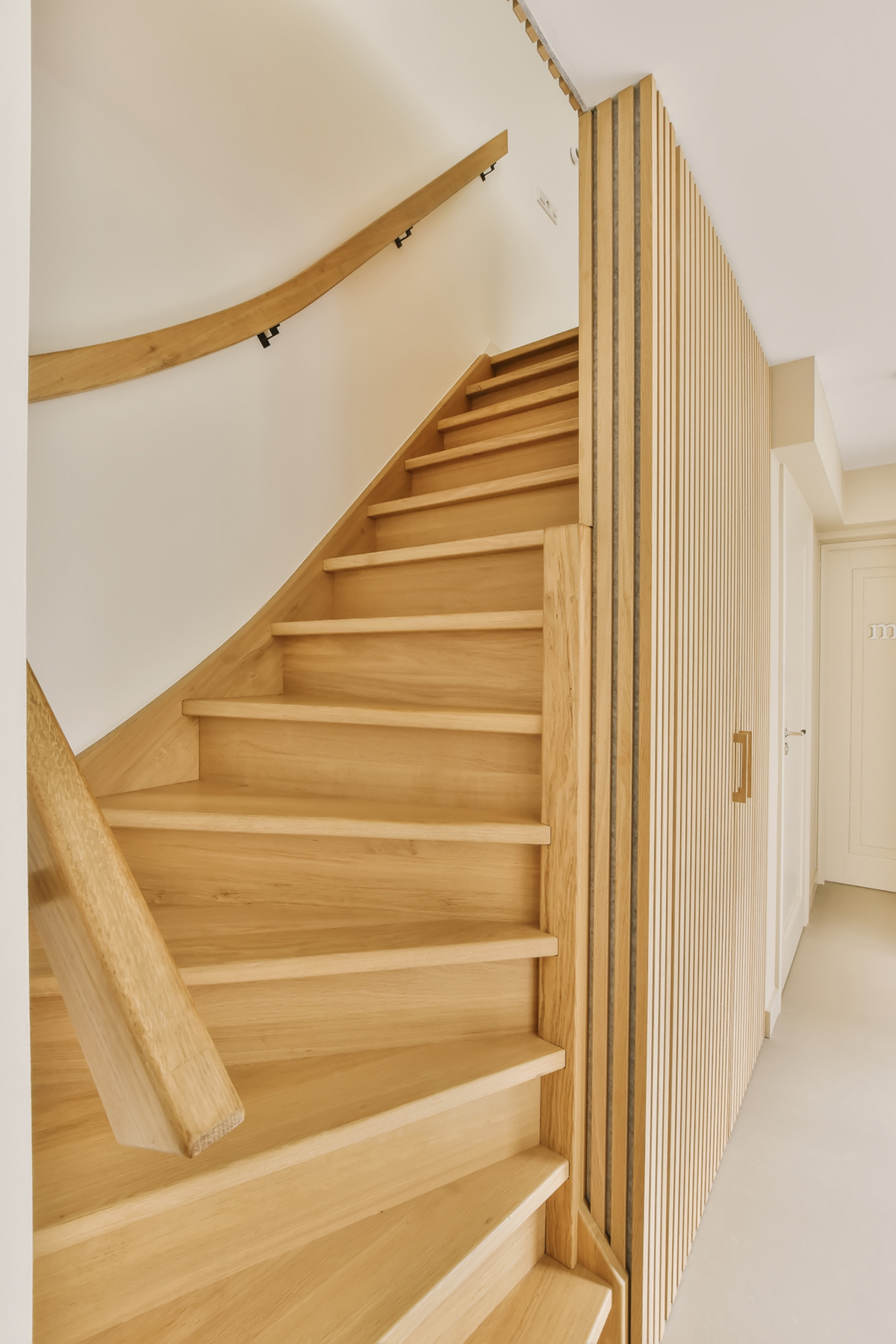a wooden staircase in a white room with light wood handrails on the wall and stairs leading up to the second floor